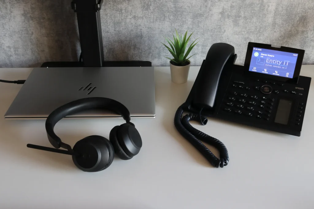 Notebook, Headset und Snom-Telefon auf einem Schreibtisch.