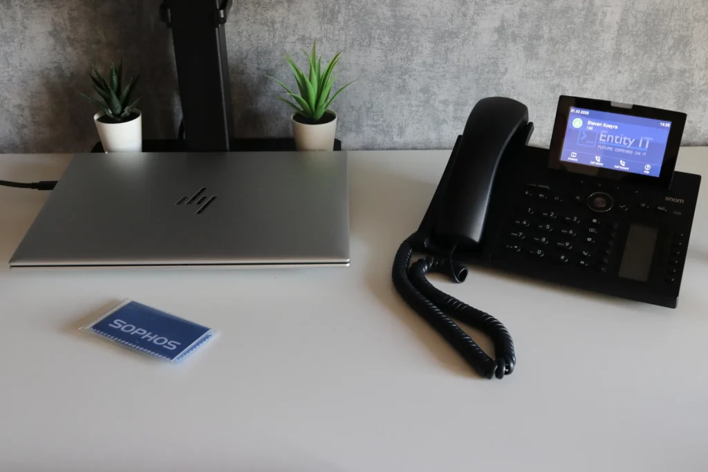 Arbeitsplatz mit HP-Notebook und Snom-Telefon mit Entity-IT auf dem Display.